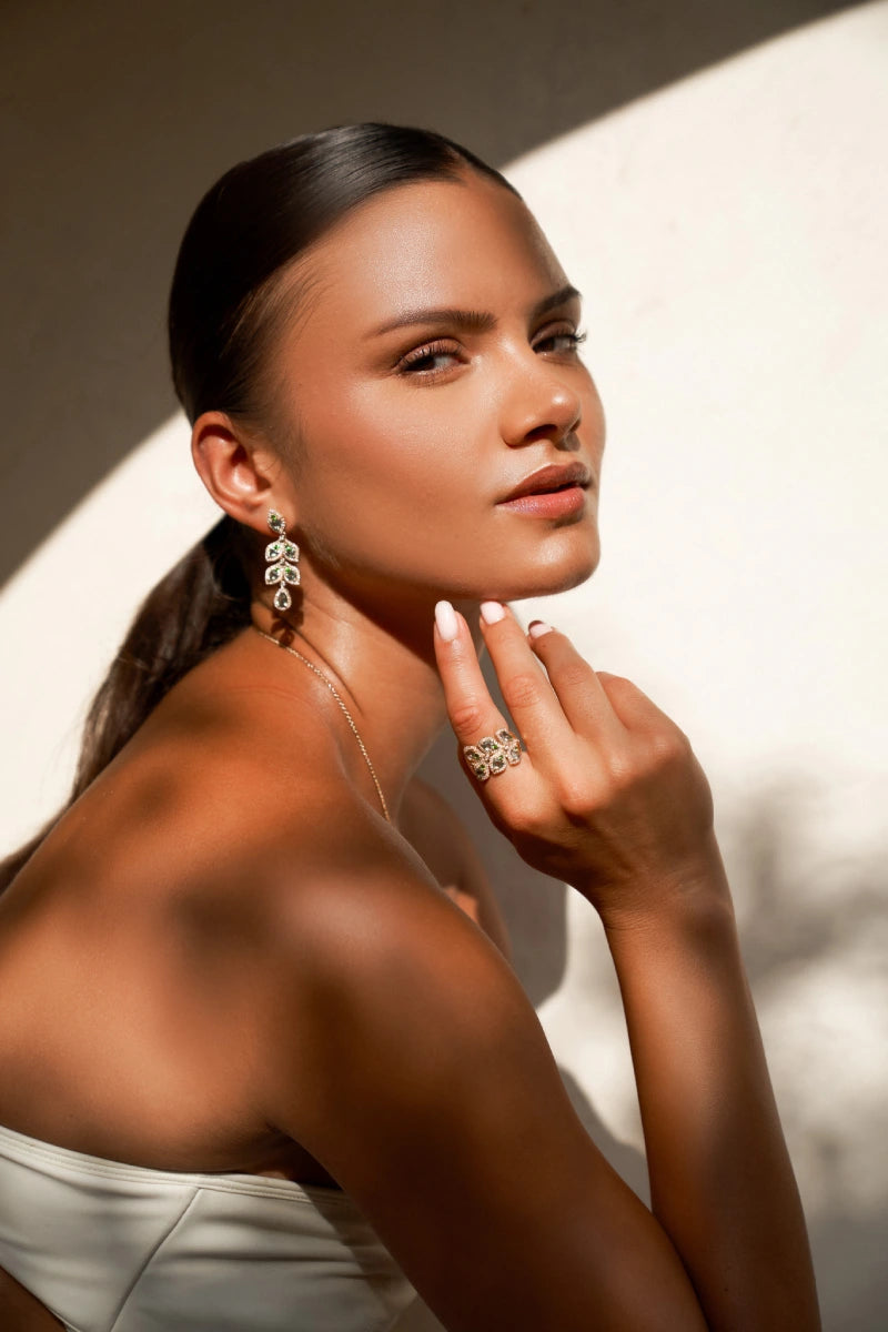 Woman wearing earrings and a ring with a neutral background